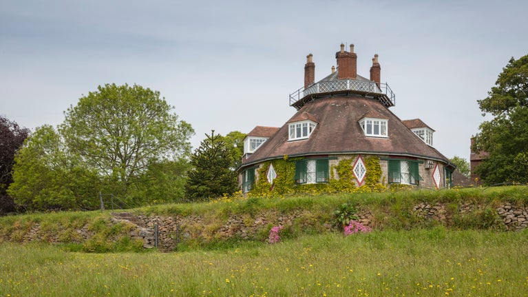 View of the octagonal house at A la Ronde with trees and flowering meadow